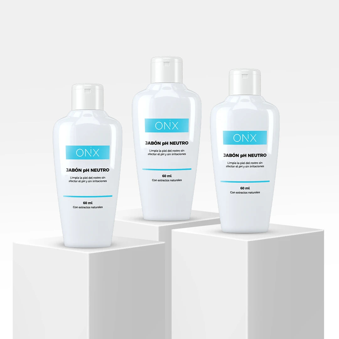 Tres envases de Jabón PH Neutro de Onix Skincare con etiquetas azules, presentados sobre cubos blancos, destacando el producto.